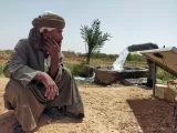 أحد المزارعين بجوار ماكينة رفع مياه بإستخدام الطاقة الشمسية يتابع تدفق المياه الجوفية لري الأرض الصحراوية بحاجر قرية القارة.