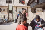 Un homme et une femme avec un enfant, devant un bâtiment, en train de discuter.