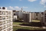 Vue d'un quartier urbain avec des bâtiments modernes et un ciel nuageux.