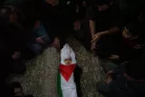  [fr] Un enfant entouré d'adultes, emmailloté dans un drapeau palestinien. Atmosphère solennelle. [it] Un bambino circondato da adulti, avvolto in una bandiera palestinese. Atmosfera solenne. 