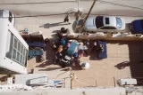 Vue aérienne d'une cour encombrée de déchets et de personnes, avec des voitures garées.
