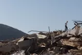Des débris de bâtiments effondrés, des personnes marchent sur les ruines.