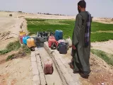 A farmer next to a groundwater outlet from a petrol engine