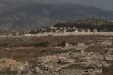 Des ruines et des collines, avec un mur et des graffitis au loin.