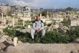 Un homme assis au milieu d'un cimetière en ruines, entouré de tombes et de végétation.