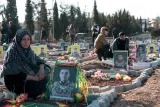 در این تصویر، مردمی در یک گورستان دیده می‌شوند که در کنار قبرهای سربازان نشسته‌اند. قبرها با عکس‌های بزرگ از افراد فوت شده و گل‌های تزئینی پوشانده شده‌اند. برخی از افرادی که در تصویر حضور دارند حالت تأملی دارند و به یاد عزیزان خود نشسته‌اند. فضای کلی تصویر حاکی از غم و اندوه ناشی از فقدان است. در پس‌زمینه، درختان و زمین‌هایی وجود دارد که فضای گورستان را تشکیل داده‌اند.