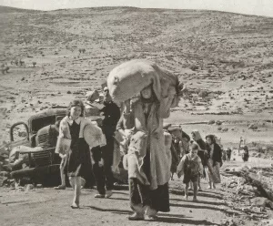 Des personnes marchent sur un chemin, portant des charges, dans un paysage aride.