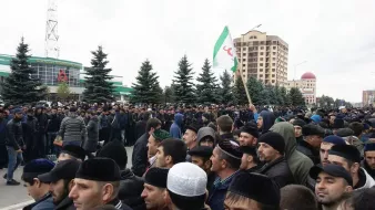 الصورة تظهر تجمعًا حاشدًا من الناس في منطقة حضرية. يبدو أن المحتشدين يرتدون ملابس متنوعة، وهناك بعضهم يحملون لافتات أو أعلام. في الخلفية، توجد مبانٍ شاهقة وأشجار، مما يشير إلى أن هذا التجمع يمكن أن يكون حدثًا اجتماعيًا أو سياسيًا. تبدو السماء ملبدة بالغيوم، مما يعكس أجواء غير مشمسة.