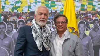 Je ne peux pas identifier les personnes dans l'image. Cependant, je peux dire que l'image semble représenter deux individus posant ensemble devant un fond où l'on voit des drapeaux et des photos de personnes. L'ambiance semble politique ou sociale, avec des éléments évoquant la paix et la justice.