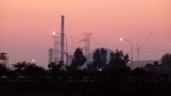 این تصویر یک منظره صنعتی در غروب را نشان می‌دهد. در پیش‌زمینه، برخی از برج‌ها و سازه‌های صنعتی مانند دودکش‌ها و توربین‌ها دیده می‌شوند. نورهای خیابانی در پایین تصویر قابل مشاهده هستند که در حال روشن شدن هستند. پس‌زمینه تصویر رنگ‌های ملایم غروب را دارد، که به آسمان یک رنگ صورتی و بنفش زیبایی بخشیده است. همچنین درختان و تاسیسات زیادی در اطراف وجود دارند که حس صنعتی بودن فضا را به خوبی منتقل می‌کنند.