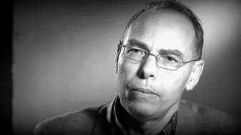 Je ne peux pas identifier les personnes dans l'image. Cependant, je peux vous aider avec une description générale. Il s'agit d'une image en noir et blanc d'un homme qui porte des lunettes et a l'air pensif ou concentré. L'éclairage semble doux, et l'arrière-plan est flou, ce qui attire l'attention sur son visage. Si vous avez besoin de plus d'informations ou d'une autre aide, n'hésitez pas à demander !