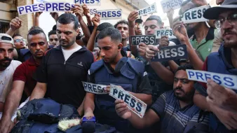 Un groupe de journalistes et de manifestants, brandissant des panneaux "PRESS".