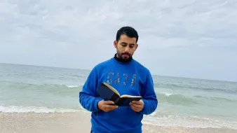 در این تصویر، مردی در کنار دریا ایستاده است و یک کتاب در دست دارد. او لباسی آبی رنگ به تن دارد که روی آن کلمه "GAZA" به چشم می‌خورد. پس‌زمینه تصویر را دریای آرام و آسمانی ابری تشکیل می‌دهد. موج‌های دریا به ساحل می‌رسند و فضای آرامی را به تصویر بخشیده‌اند. 