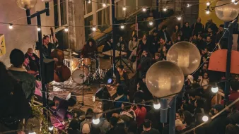 Concert animé dans un lieu chaleureux, éclairé par des guirlandes lumineuses.