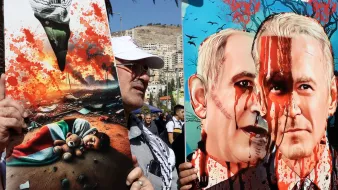 تظهر الصورة شخصين يحملان لوحات فنية في سياق احتجاج أو فعالية عامة. اللوحة على اليسار تصور طفلاً ممددًا على الأرض وسط دمار وخراب، مما يعكس مشاعر الألم والفقد. أما اللوحة على اليمين فتظهر وجهين لرجلين، أحدهما يبدو مثل شخصية معروفة، محاطًا بدماء، مما يعكس رسالة قوية تتعلق بالصراع أو السياسة. الأجواء العامة تعكس توترًا وعواطف قوية تعبر عن مواقف سياسية أو اجتماعية.
