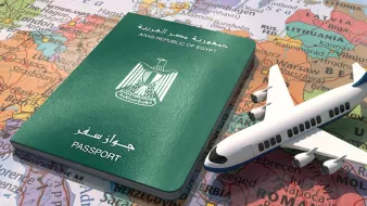 L'image montre un passeport égyptien, de couleur verte, posé sur une carte du monde. À côté du passeport, il y a un petit modèle d'avion, symbolisant le voyage et l'exploration. La carte en arrière-plan présente divers pays et continents, suggérant des destinations possibles. L'ensemble évoque le thème du voyage international et de la découverte.