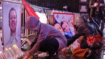 تصویر فضای یک تجمع یادبود را نشان می‌دهد که در آن افراد در حال قرار دادن شمع و گل هستند. در جلوی آنها، تصاویری از یک فرد و یک خانواده به نمایش گذاشته شده است. باران به زمین می‌ریزد و خیابان براق است. افراد با لباس‌های گرم و کلاه روی زمین نشسته‌اند و به یاد افرادی که از دست رفته‌اند، مراسمی برگزار می‌کنند. این صحنه حال و هوای غم و اندوه را منتقل می‌کند.