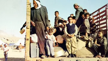 Gruppo di persone, molte famiglie e bambini, su un camion in un contesto di crisi.