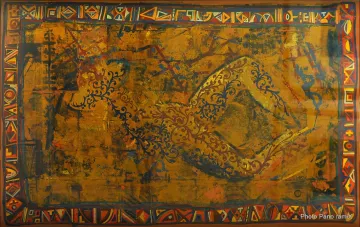 L'image semble être une œuvre artistique riche en couleurs et en motifs. On y voit une silhouette humaine dans une position allongée, entourée de motifs ornementaux détaillés. La palette de couleurs se compose principalement de teintes dorées, avec des éléments noirs et colorés qui ajoutent une dimension vibrante. Le fond présente des textures et des symboles, suggérant une inspiration culturelle ou traditionnelle. L'ensemble dégage une atmosphère à la fois mystique et chaleureuse.