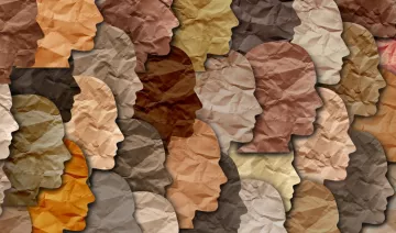 تظهر الصورة مجموعة من الوجوه البشرية المصنوعة من ورق ملتوي بألوان مختلفة تتراوح بين درجات البيج والبني. تعكس هذه الألوان تنوع البشرة، حيث يتم ترتيب الوجوه بشكل متداخل، مما يخلق تأثيرًا فنيًا مميزًا. تبرز الأشكال والظلال الملتوية، مما يعطي انطباعًا عن الحركة والتنوع الثقافي.