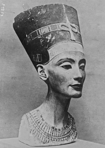 L'immagine rappresenta un busto di pietra di una figura femminile, noto per essere la regina Nefertiti, famosa per la sua bellezza e per il suo ruolo nella storia dell'antico Egitto. Il busto è caratterizzato da un copricapo distintivo e da dettagli elaborati sulla collana e sul viso. La scultura ha un aspetto realistico e raffinato, evidenziando l'arte egizia antica. Il colore della pietra è chiaro con alcune dorature, e l'espressione del volto è serena e dignitosa.