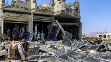 Destruction : bâtiment effondré, débris et panneaux solaires éparpillés autour.