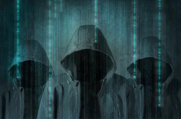 الصورة تظهر ثلاثة أشخاص يرتدون هوديات (أغطية رأس) سوداء، وجوههم غير مرئية. خلفهم يوجد تدرجات من الألوان الزرقاء تشبه البيانات الرقمية المتساقطة، مما يعطي انطباعًا عن بيئة إلكترونية أو تكنولوجية. الأجواء العامة للصورة توحي بالغموض أو الإخفاء.