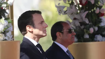 این تصویر دو مرد را در کنار هم نشان می‌دهد. شخصی در سمت چپ با موهای تیره و لباس رسمی مشکی، در حالت تفکر و جدی ایستاده است. در سمت راست، مرد دیگری با عینک آفتابی و لباس رسمی به رنگ تیره، در کنار او قرار دارد. پس‌زمینه شامل گل‌های سفید و عناصر طبیعی است که به تصویر زیبایی و شکیل بودن می‌بخشد.