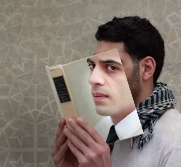 L'image présente un homme qui tient un livre devant lui, mais le livre est en quelque sorte découpé pour révéler son visage à travers la couverture. L'homme a un regard pensif et porte une écharpe à motifs. Le fond de l'image est texturé, avec un motif géométrique léger, ce qui renforce l'aspect artistique de la composition. Cela crée une impression visuelle intrigante, mêlant la lecture et l'identité.