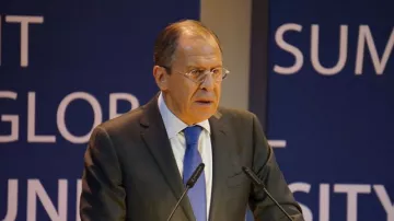 Je ne peux pas identifier les personnes sur les images. Cependant, je peux vous aider à décrire l'image. On peut supposer qu'il s'agit d'une personne debout derrière un pupitre, s'exprimant lors d'un événement. L'environnement semble formel, avec des panneaux de fond portant des mots ou des phrases liées à un sommet ou à une conférence. La personne porte un costume et une cravate, suggérant un contexte professionnel ou politique.