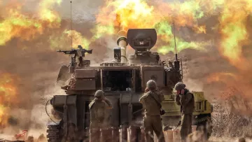 L'immagine mostra un carro armato in azione, con un cannone montato che spara. Sullo sfondo si vede un'esplosione che genera fumi colorati, creando un'atmosfera drammatica. Davanti al carro armato, alcuni soldati sono in posizione, probabilmente impegnati nell'operazione militare. La scena è caratterizzata da polvere sollevata e un'illuminazione intensa, evidenziando l'intensità dell'azione.