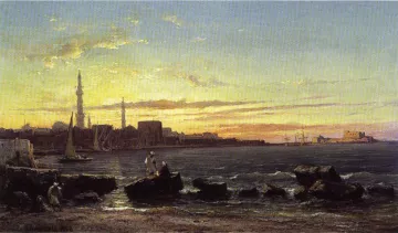 L'image représente un paysage côtier au crépuscule, avec un ciel teinté de nuances dorées et orangées. À gauche, des navigateurs près des rochers et un voilier sont visibles, tandis qu'à droite, des silhouettes de bâtiments et de structures portuaires se dessinent sur l'horizon. La lumière du soleil couchant reflète sur l'eau calmes, créant une atmosphère paisible et sereine. Le tout évoque une scène maritime typique, avec une harmonie entre la nature et l'activité humaine.