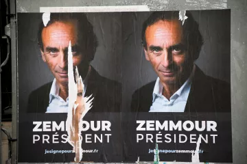 L'image montre une affiche politique présentant un homme qui se présente comme candidat à la présidence. Le visage est affiché en gros plan, et le nom "Zemmour" est écrit en grandes lettres sous le mot "PRÉSIDENT". L'affiche semble avoir été partiellement déchirée, ce qui donne un aspect usé et détérioré. On peut également remarquer un fond sombre qui met en avant le sujet de l'affiche.