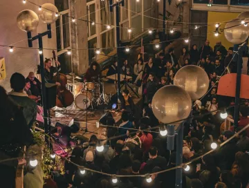 Concert animé dans un lieu chaleureux, éclairé par des guirlandes lumineuses.